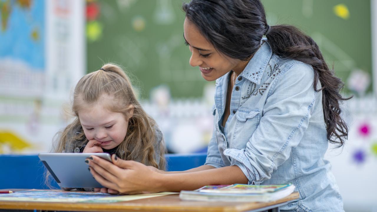 Teacher using tablet with student