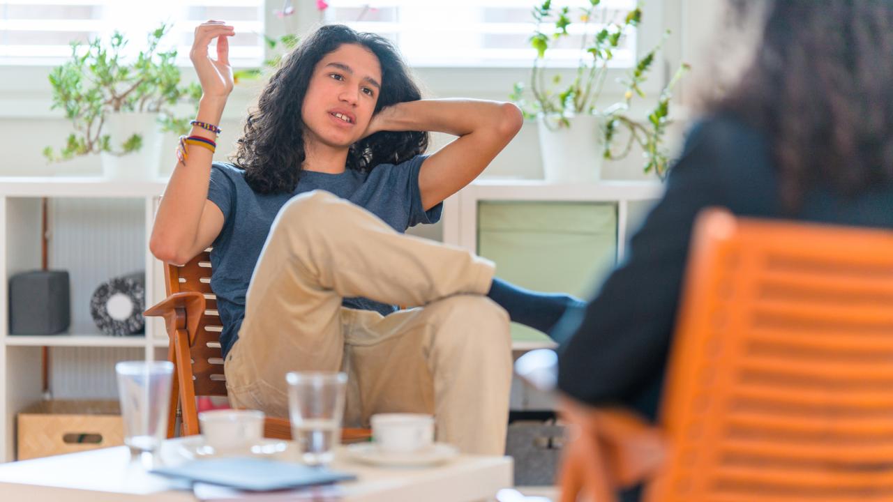 man sitting in chair talking to woman