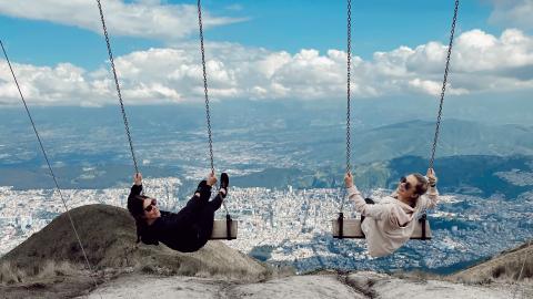two friends on swings in the mountains